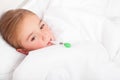 Sick girl resting in bed with fever meassuring temperature with