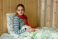 A sick girl sits in bed and looks tiredly out the window Royalty Free Stock Photo