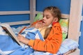 Sick girl sneezes lying in bed and reading a book