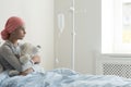 Sick girl wearing headscarf and hugging plush toy in the hospital Royalty Free Stock Photo