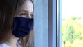Sick Girl Wearing Protective Mask in Coronavirus Pandemic, Sad Child Looking on Window, Unhappy Bored Kid in Covid-19 Crisis Royalty Free Stock Photo