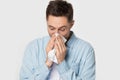 Sick guy holding handkerchief sneezing wiping nose studio shot Royalty Free Stock Photo