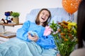 Sick, hospital patient and visitor with flowers at bed with a woman in recovery with support. Healthcare, medical
