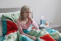 Sick ill kid girl with fever lying in bed at home with flu, fever, running nose and coughing in hand fist. Virus cold season flu Royalty Free Stock Photo