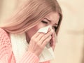 Sick ill woman in autumn park sneezing in tissue.