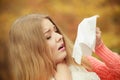 Sick ill woman in autumn park sneezing in tissue. Royalty Free Stock Photo