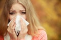 Sick ill woman in autumn park sneezing in tissue. Royalty Free Stock Photo