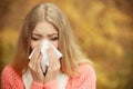 Sick ill woman in autumn park sneezing in tissue. Royalty Free Stock Photo