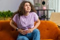 Sick ill woman suffering from period cramps, stomach ache menstrual pain lying on sofa at home room Royalty Free Stock Photo