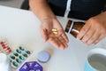 Sick illness woman hold two pill on hand pouring capsules from medication bottle take painkiller supplement medicine