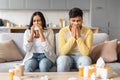 Sick indian couple sitting on sofa, blowing noses and suffering from colds Royalty Free Stock Photo