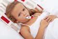 Sick kid in bed holding thermometer between lips Royalty Free Stock Photo