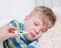 Sick kid with high fever laying in bed and mother taking tempera Royalty Free Stock Photo