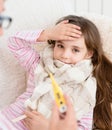 Sick kid with high fever laying in bed and mother taking temperature Royalty Free Stock Photo