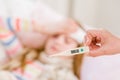 Sick kid with high fever lying in bed and mother taking temperature Royalty Free Stock Photo