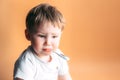 Sick kid with a thermometer in his mouth with sad face on orange background Royalty Free Stock Photo