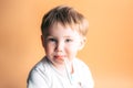 Sick kid with a thermometer in his mouth with sad face on orange background Royalty Free Stock Photo