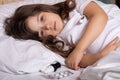 Sick kid with thermometer laying in bed and taking temperature. Checking temperature using thermometer. Royalty Free Stock Photo