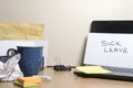 Sick leave message left on a messy office desk