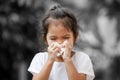 Sick little asian girl wiping or cleaning nose with tissue