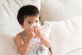 Sick little Asian girl wiping or cleaning nose with tissue
