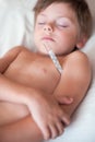 Sleeping sick small boy lying with a thermometer in the armpit Royalty Free Stock Photo