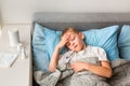 Sick little boy with high fever and headache laying in bed and holding thermometer in his mouth. Stay at home during corona virus Royalty Free Stock Photo