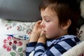 Sick little child, boy, with high fever sleeping on the couch at Royalty Free Stock Photo