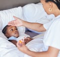 Sick little girl in bed while her mother uses a thermometer to check her temperature. Black single parent feeling