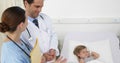 Sick little girl lying in bed with nurse and doctor