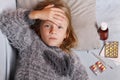 Sick girl lying in bed with a thermometer and medicine. Child winter flu allergy health care concept