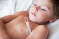 Sick little kid lying with a thermometer with high temperature in the armpit Royalty Free Stock Photo