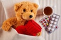 Sick teddy bear lying in bed with hot water bottle Royalty Free Stock Photo