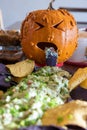 A sick looking pumpkin throwing up green stuff on a plate of chips Royalty Free Stock Photo