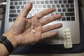 Sick male home office worker taking pills in front of his working space, during his working deadline night. Royalty Free Stock Photo
