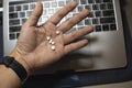 Sick male home office worker taking pills in front of his working space, during his working deadline night. Royalty Free Stock Photo