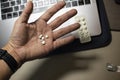 Sick male home office worker taking pills in front of his working space, during his working deadline night. Royalty Free Stock Photo