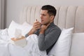 Sick man with box of paper tissues suffering from cold in bed at home Royalty Free Stock Photo