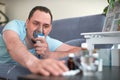 A sick man breathes through an inhaler mask. lying on the couch and pulls his hand to the cure Royalty Free Stock Photo