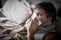Sick man with cold lying in bed and blow nose. Royalty Free Stock Photo