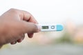 Sick man holds digital thermometer with body temperature reading in Fahrenheit up close to the camera