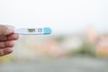 Sick man holds digital thermometer with body temperature reading in Fahrenheit up close to the camera