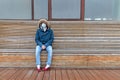 Sick man with hood sitting alone on bench, wearing facial mask. Life in isolation, quarantine, coronavirus pandemic