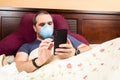 Sick man laying in bed using smarthphone