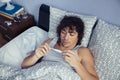 Sick man looking temperature in thermometer on bed Royalty Free Stock Photo