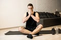 Sick man with runny nose sitting on black yoga mat. Stay home concept. Brunette young man blows his nose after workout