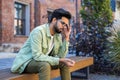 Sick man sitting on bench outside office building, Indian man having severe headache and dizziness migraine, overworked Royalty Free Stock Photo