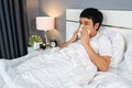 Sick man sneezing into tissue lying in bed Royalty Free Stock Photo