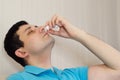 Sick Man spraying nasal medical drops in his nose. Flu cold, Rhinitis, or allergy symptom.