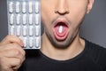 Sick man with wide open mouth has capsule on his tongue and holds blister up next to his face  while taking pill against pain Royalty Free Stock Photo